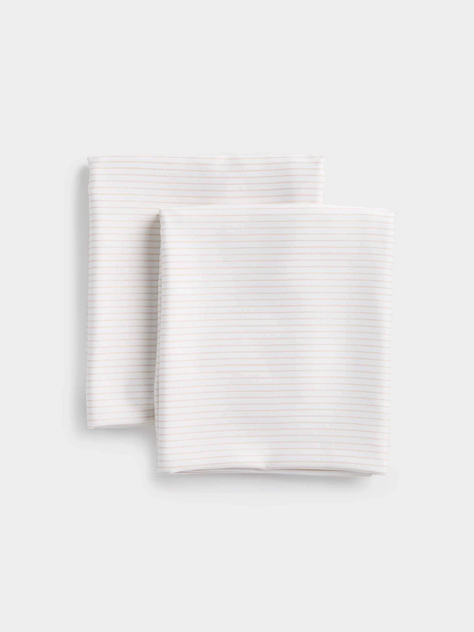 Two bamboo pillowcases from Cozy Earth, neatly stacked on a light gray background, featuring a subtle striped design. 