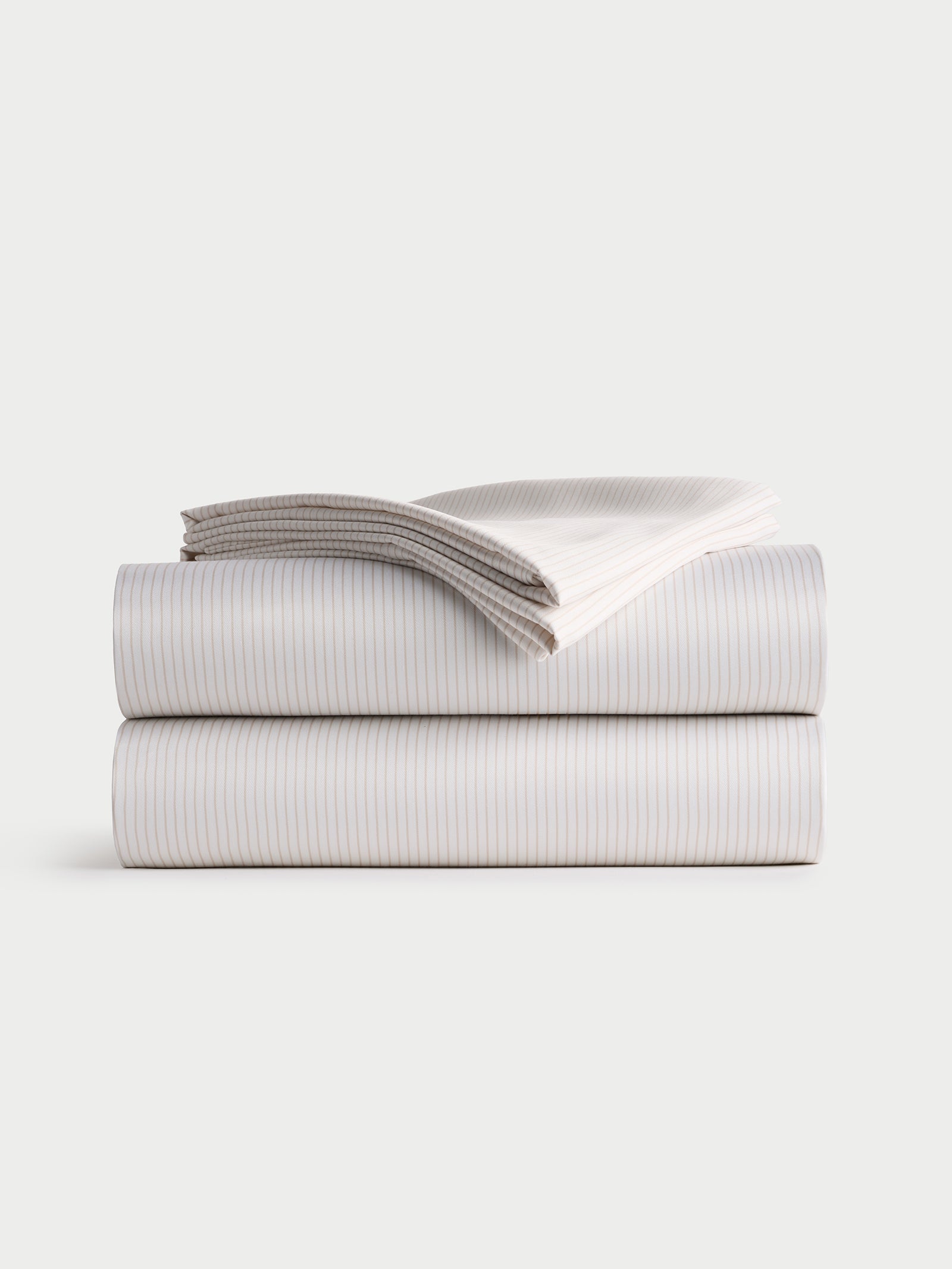 A neatly folded Bamboo Sheet Set by Cozy Earth, featuring a fitted sheet, flat sheet, and two pillowcases with a striped design, stacked on a plain white background. 