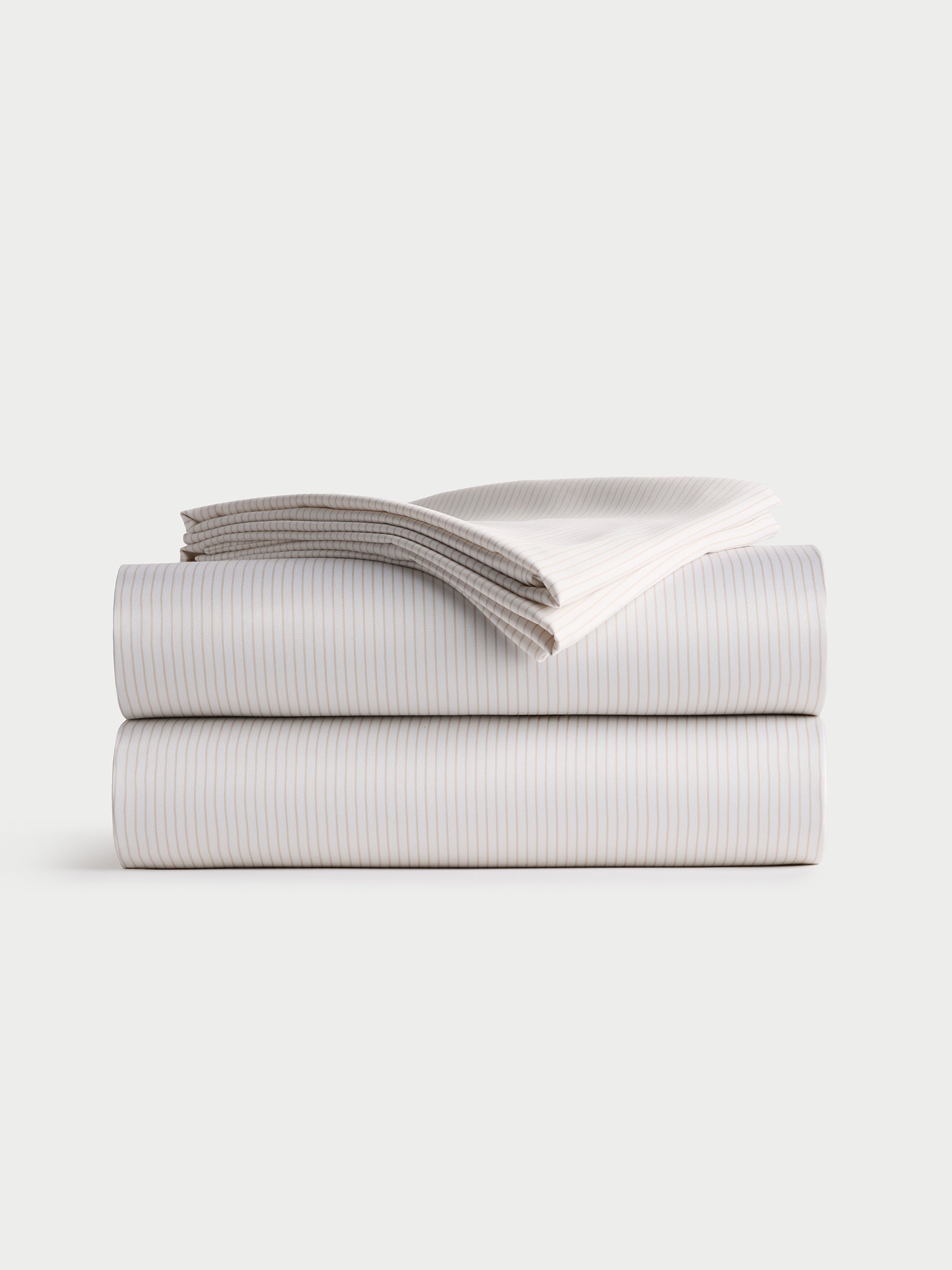 A neatly folded Bamboo Sheet Set by Cozy Earth, featuring a fitted sheet, flat sheet, and two pillowcases with a striped design, stacked on a plain white background. |Color:Driftwood Pinstripe