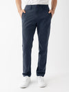 A person is standing against a white background, wearing Cozy Earth's Men's Everywhere Pant 30L in navy blue, a white t-shirt, and white sneakers. Their hands are in the pockets of the pants, and the image captures them from the waist down. |Color:Eclipse