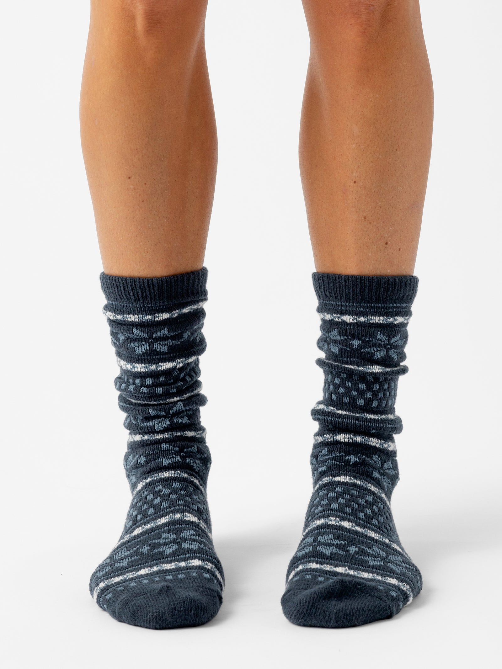 A person stands facing forward with a white background wearing Snowflake Plush Lounge Socks in Eclipse 