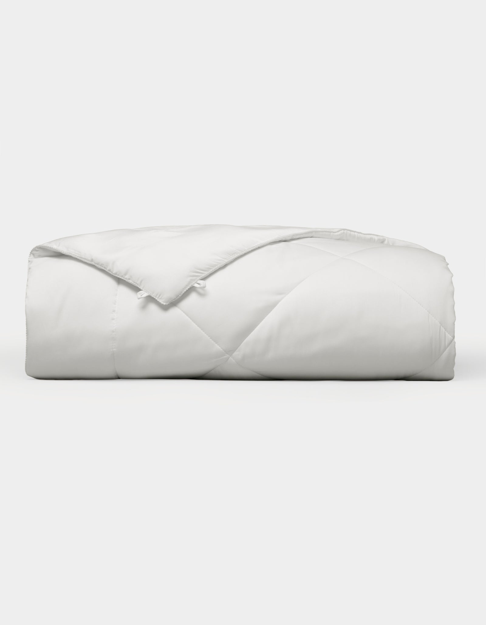 The Cozy Earth Bamboo Viscose Comforter, featuring a quilted design, is neatly folded and displayed against a plain white background. 