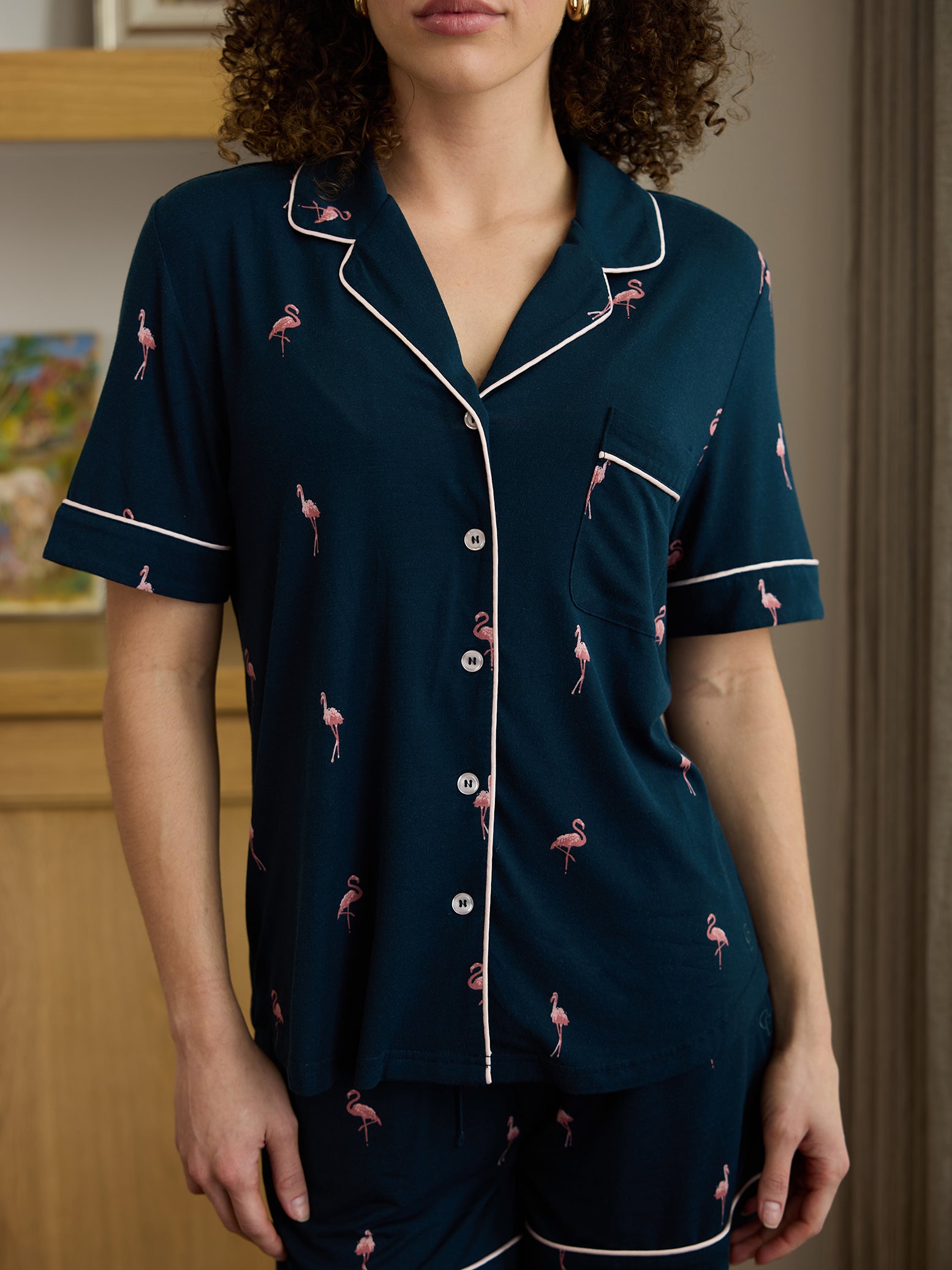 Woman in living room wearing short sleeve flamingo print pajama top 