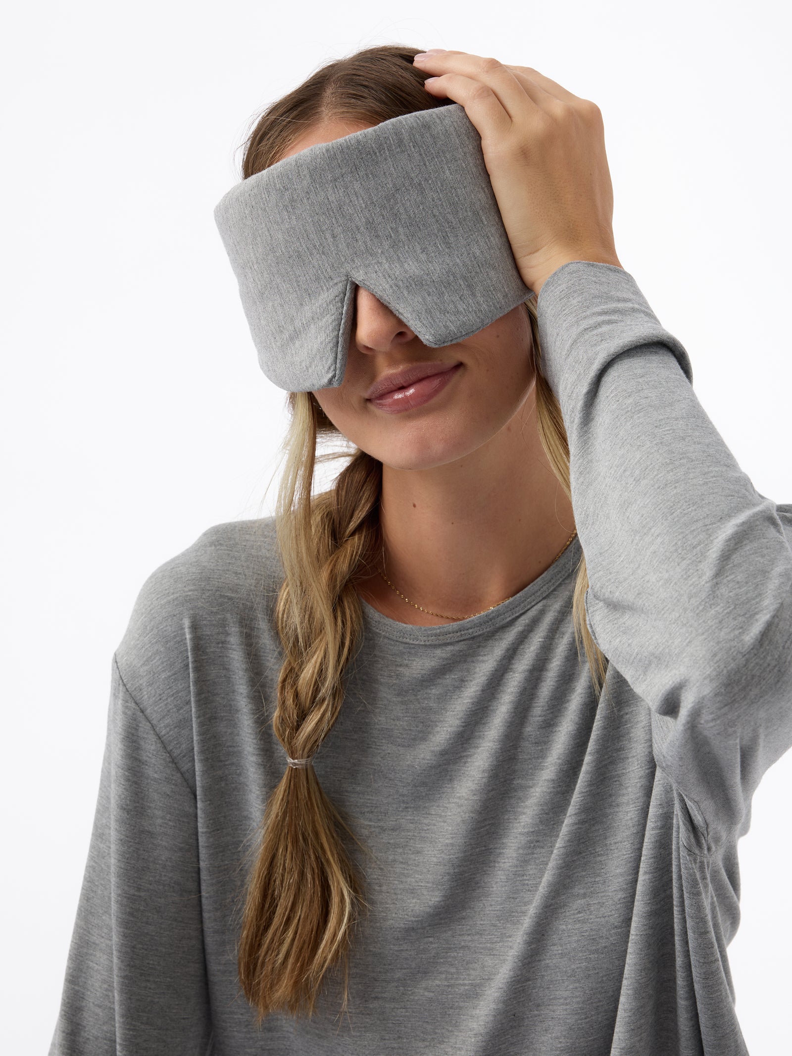 A woman wears the Cozy Earth Adjustable Bamboo Sleep Mask in Grey. 