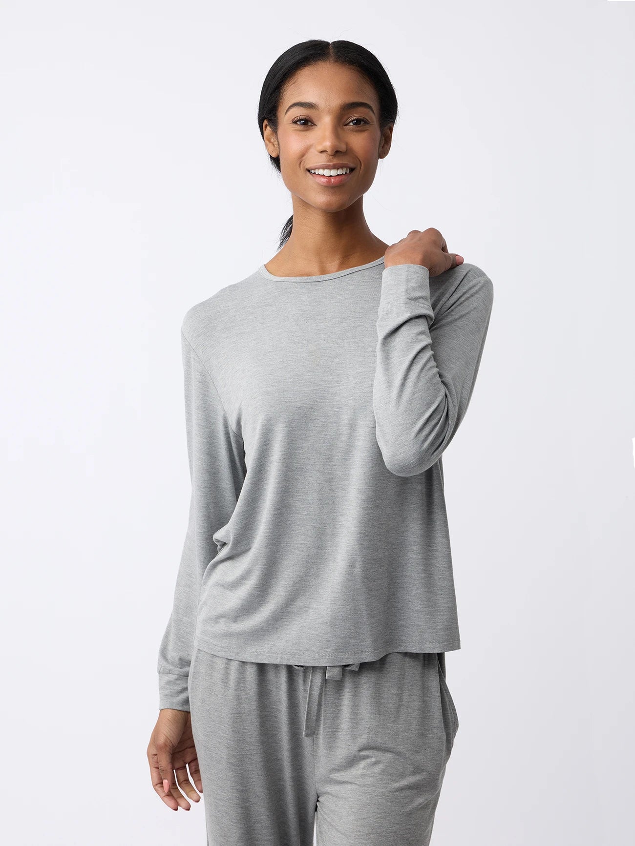 A woman in a Cozy Earth Women's Stretch Knit Bamboo Long Sleeve Lounge Tee and matching pants smiles at the camera against a plain white background. |Color:Grey