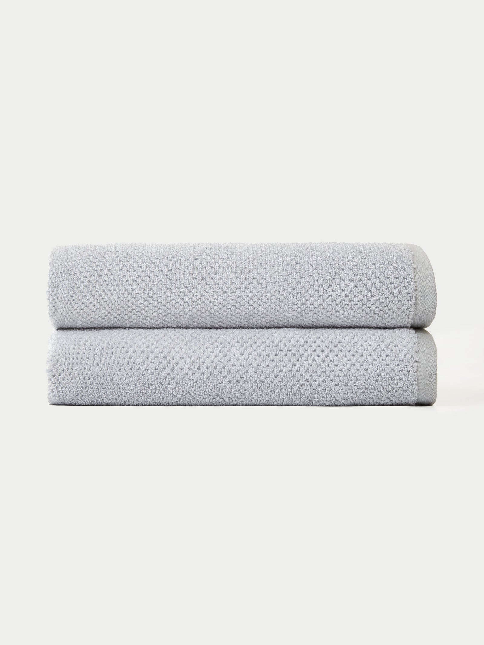 The Nantucket Bath Towel Set by Cozy Earth features two neatly folded light gray towels stacked together against a plain white background.