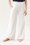 On a light background, someone wears Cozy Earth's Women's Ultra-Soft Bamboo Wide Leg Pull On Pant & Pullover Set in navy blue, featuring white wide-legged pants with an elastic waistband. The person is barefoot, with one hand in a pocket. |Color:Ivory