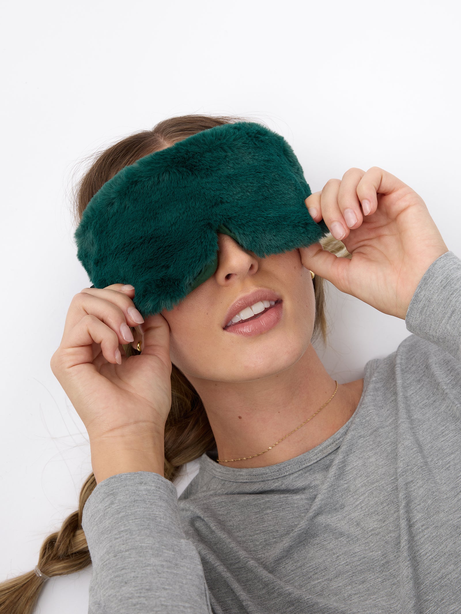 A woman wears the Cozy Earth Faux Fur Sleep Mask in Jade. 