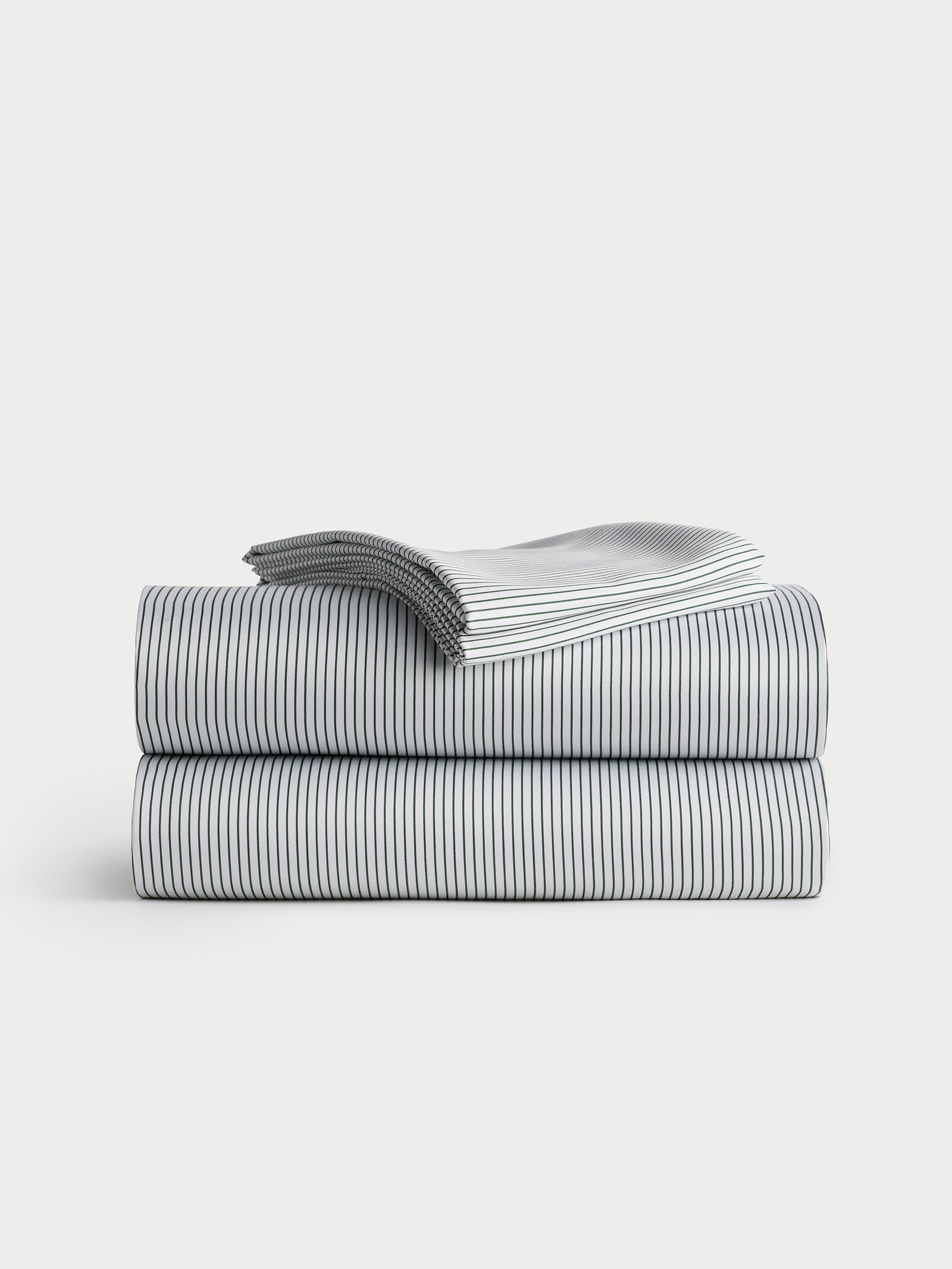 A neatly folded stack of the Bamboo Sheet Set by Cozy Earth, featuring a thin black striped pattern on a white background, is placed on a light grey surface. 