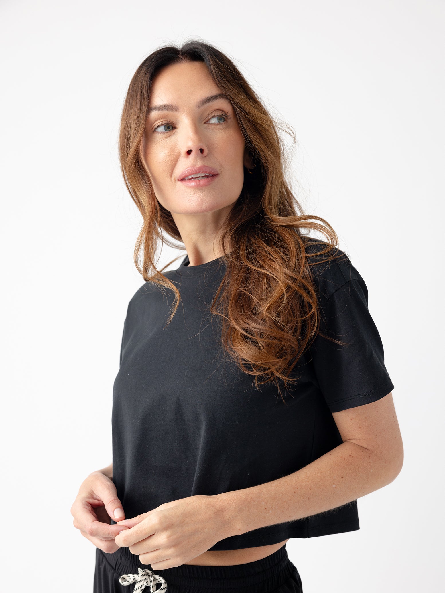 Jet Black All Day Cropped Tee. The photo of the All Day Cropped Tee is taken with a with a white background and is worn by a woman. |Color:Jet Black