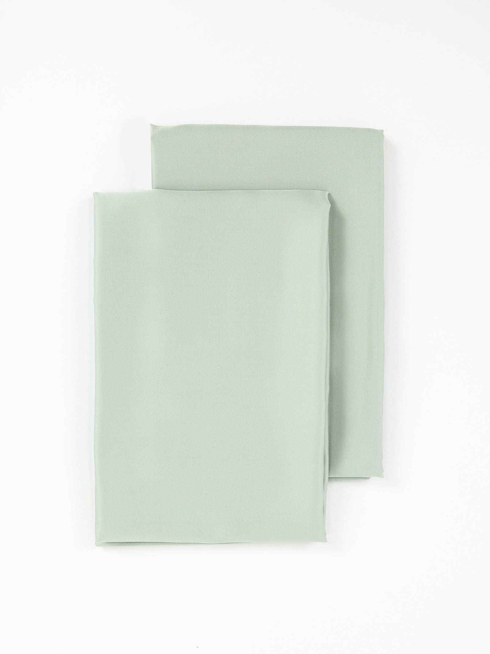 Two neatly folded light green Bamboo Pillowcases from Cozy Earth are positioned on a plain white background, showcasing their smooth, soft texture and clean edges.