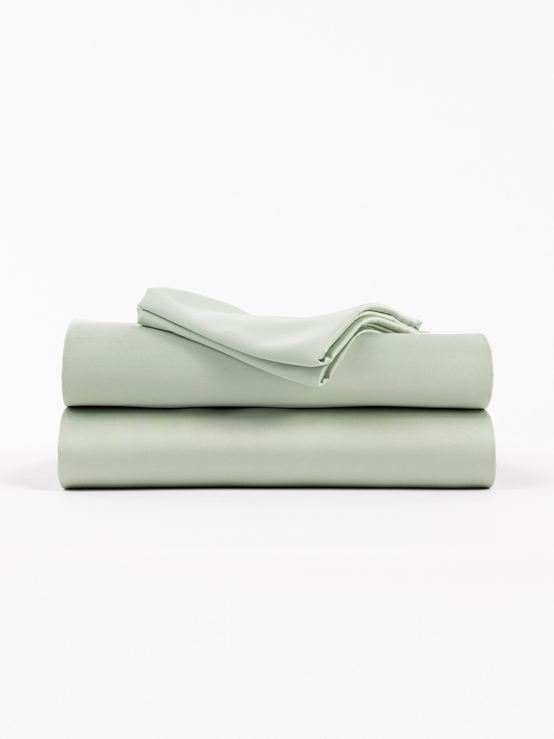 A neatly folded stack of Cozy Earth's Bamboo Sheet Set in Laurel against a white background features smooth, crisp sheets, including two larger pieces and one smaller folded top piece. |Color:Laurel