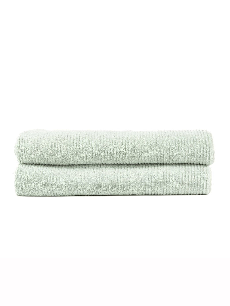 Two Ribbed Terry Bath Sheets by Cozy Earth, neatly folded in light green, are stacked together against a plain white background.
