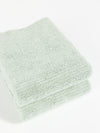 Two neatly folded Ribbed Terry Hand Towels by Cozy Earth in light green are stacked on top of each other against a plain white background. The towels appear soft and fluffy with a simple, textured pattern. |Color:Laurel