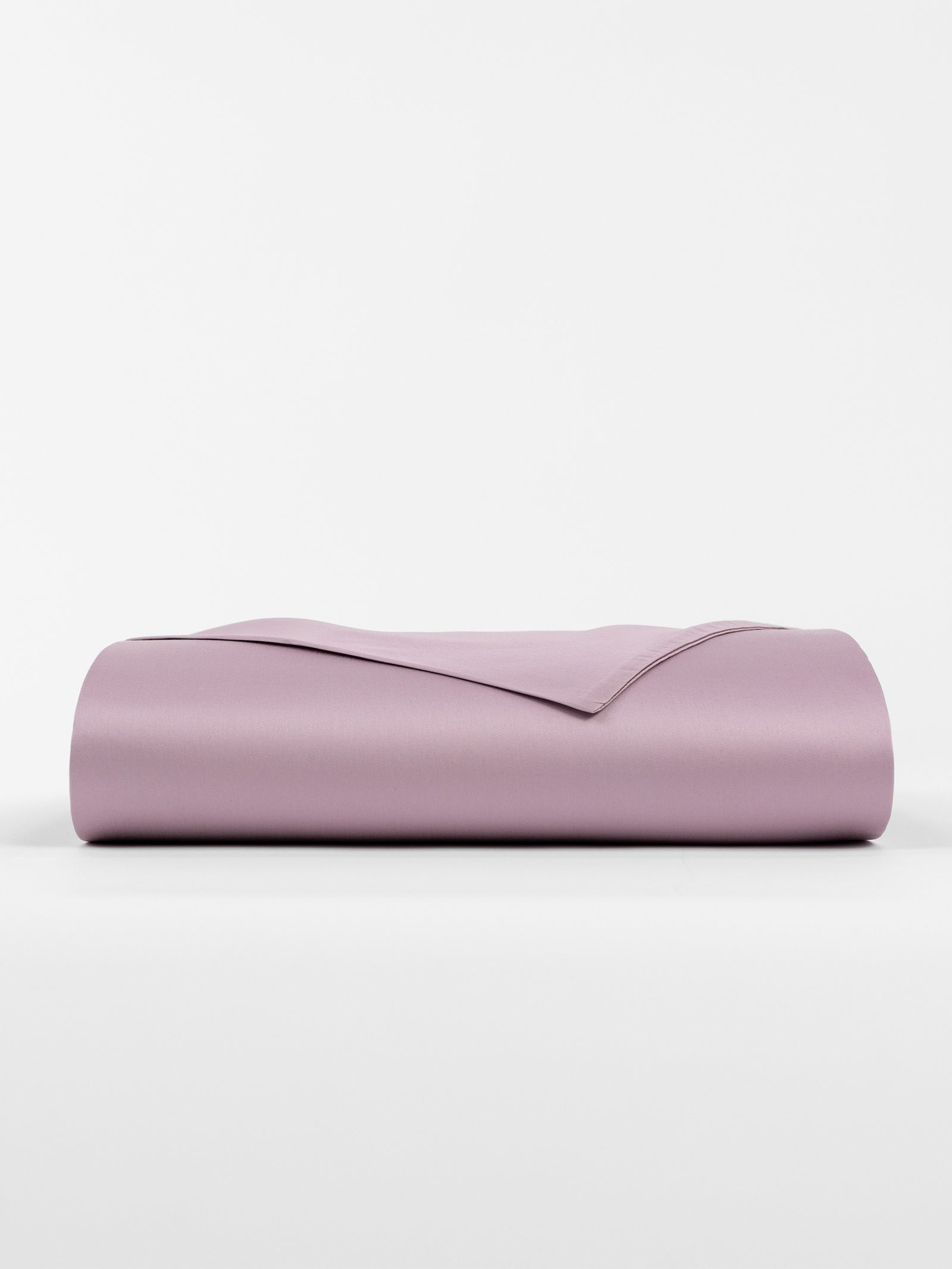 The Bamboo Flat Sheet by Cozy Earth is folded neatly on a white background, showcasing a smooth and clean light purple appearance. 