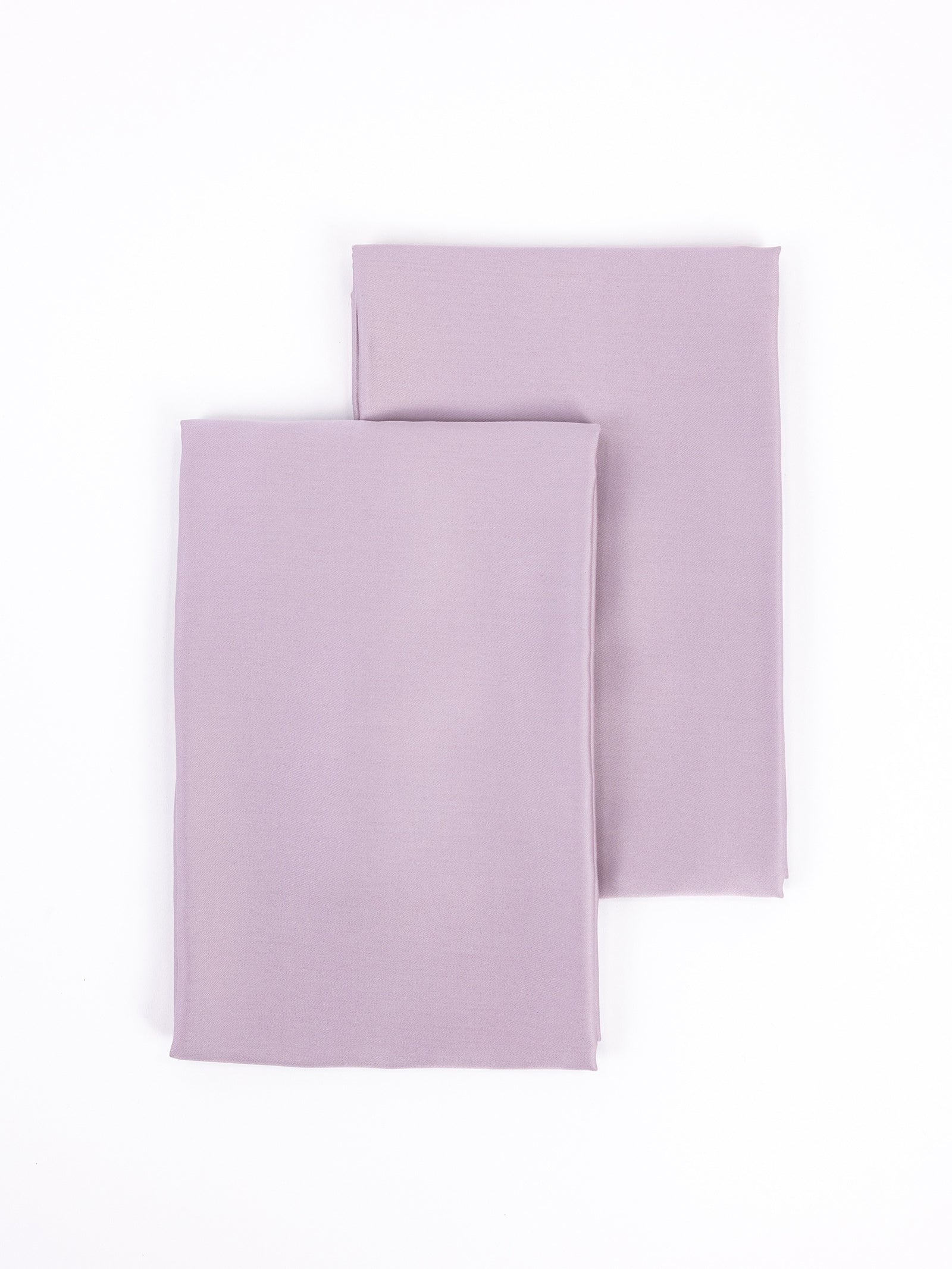 Two bamboo pillowcases from Cozy Earth, in lavender color, are laid out on a white background with one slightly overlapping the other. 