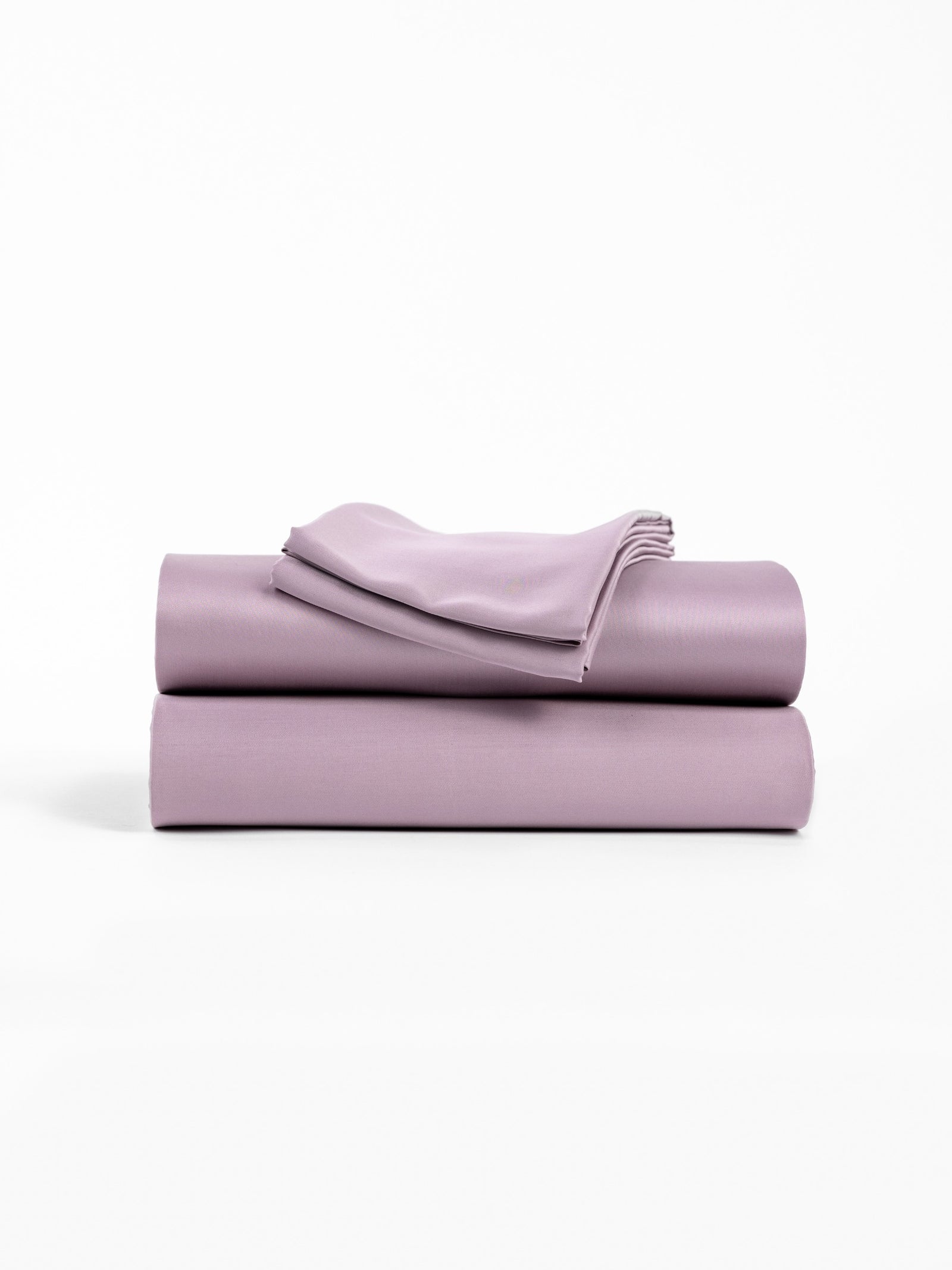 A neatly folded stack of Cozy Earth's Bamboo Sheet Set in Lavender, featuring two larger pieces and one smaller piece on top, is displayed against a plain white background. 