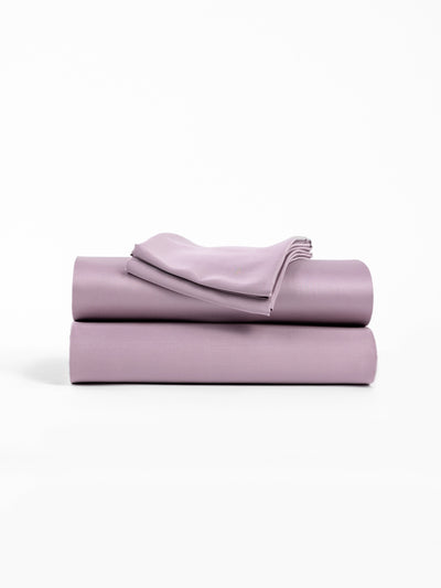 A neatly folded stack of Cozy Earth's Bamboo Sheet Set in Lavender, featuring two larger pieces and one smaller piece on top, is displayed against a plain white background. |Color:Lavender