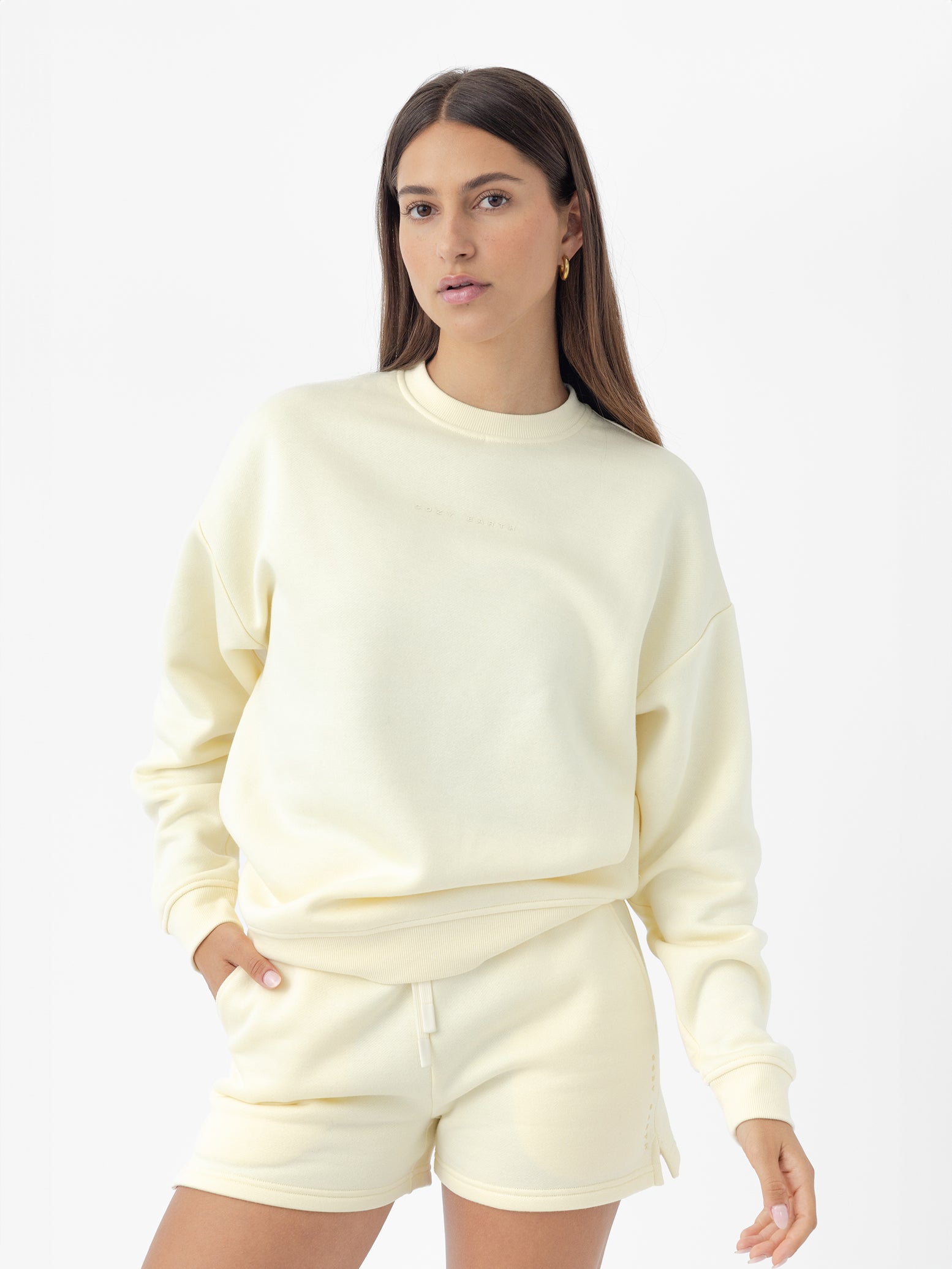 Lemonade CityScape Pullover Crew. The Pullover is being worn by a female model. Accompanying city scape clothing is being worn to complete the look of the outfit. The photo was taken with a white background. |Color:Lemonade