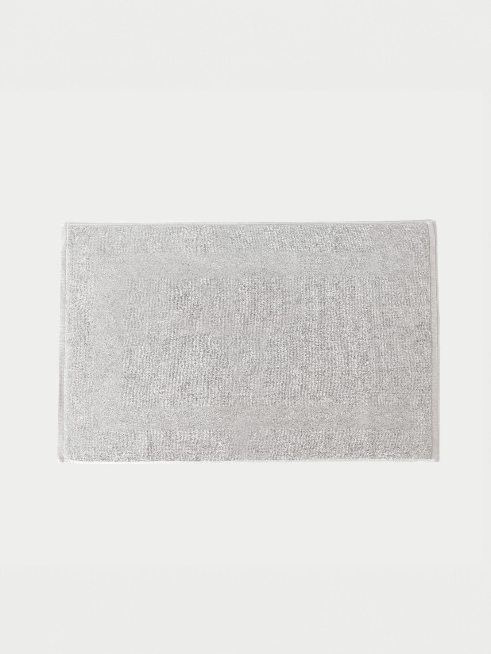 Light Grey looped terry bath mat resting on white background.