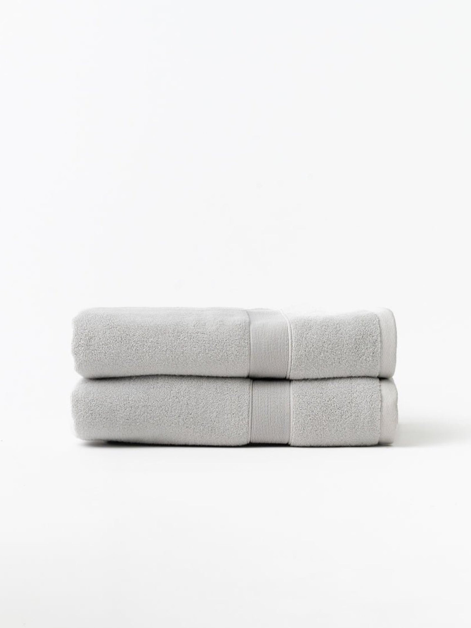 Light grey luxe bath towels folded with white background 