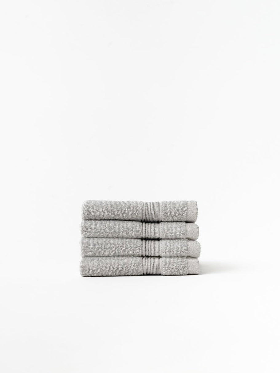 Light grey washcloths folded with white background 