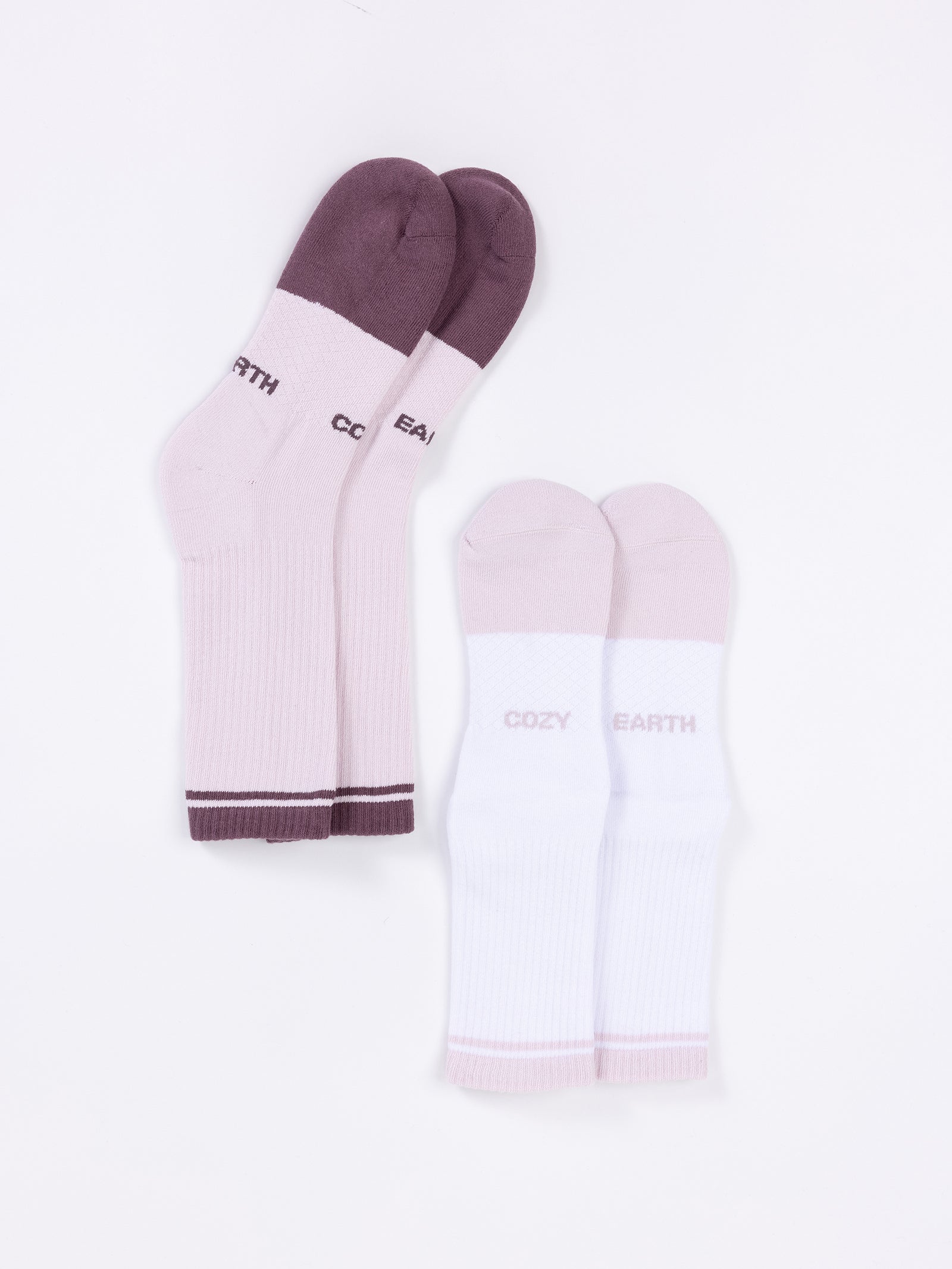 Two pairs of Essential Calf Socks from Cozy Earth are displayed side by side against a white background. The pair on the left is light purple with dark purple toes, heels, and cuffs. The pair on the right is white with light purple toes, heels, and cuffs. 