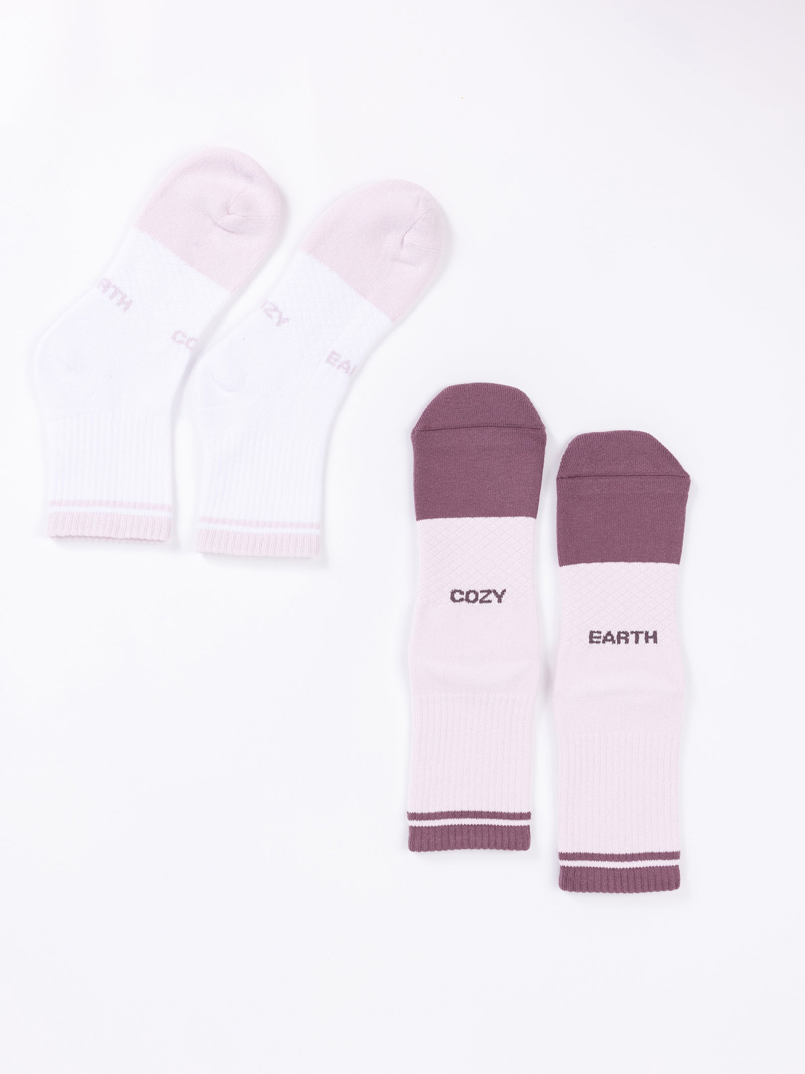 Two pairs of the Essential Quarter Sock 2-Pack from Cozy Earth are displayed on a white background. One pair is predominantly white with "COZY" and "EARTH" written in light grey, while the other pair features a combination of purple and white with "COZY" and "EARTH" written in dark grey. 