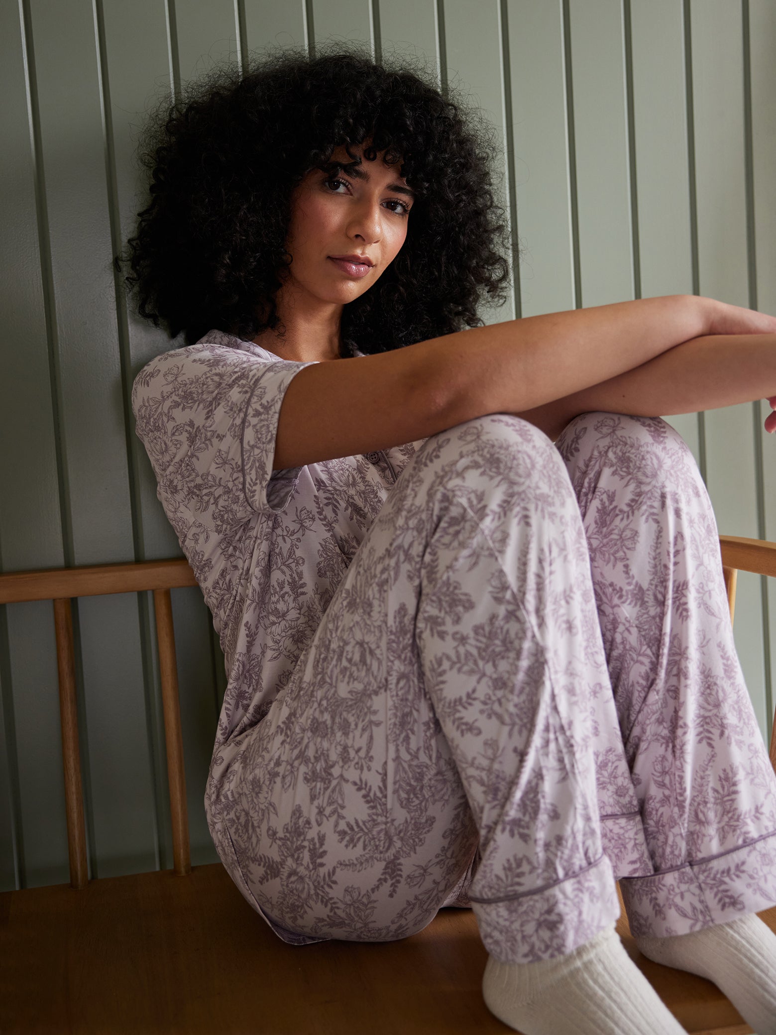 Woman sitting on bench in lilac toile pajama set 