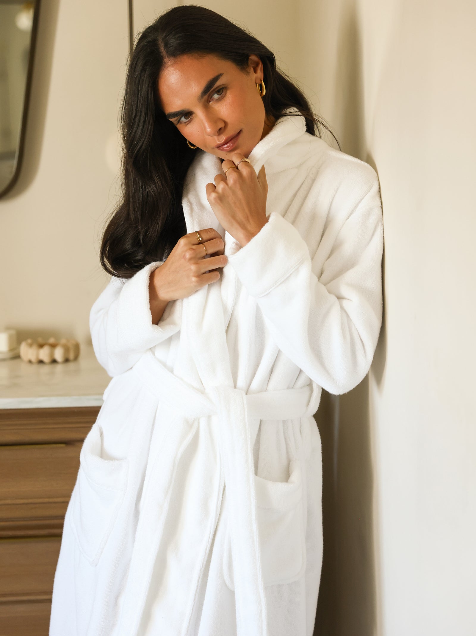 Woman standing in bathroom in white bath robe 