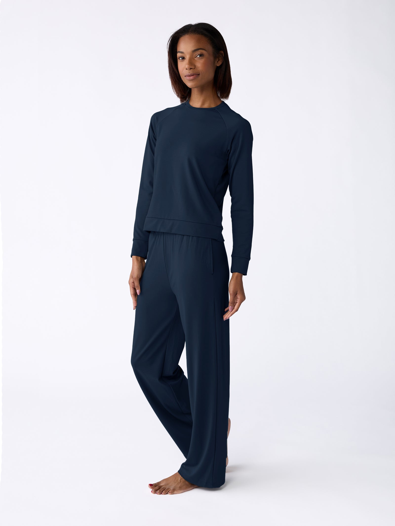 A person is barefoot against a plain white background wearing the Cozy Earth Women's Ultra-Soft Bamboo Wide Leg Pull On Pant & Pullover Crew Set in dark blue. 