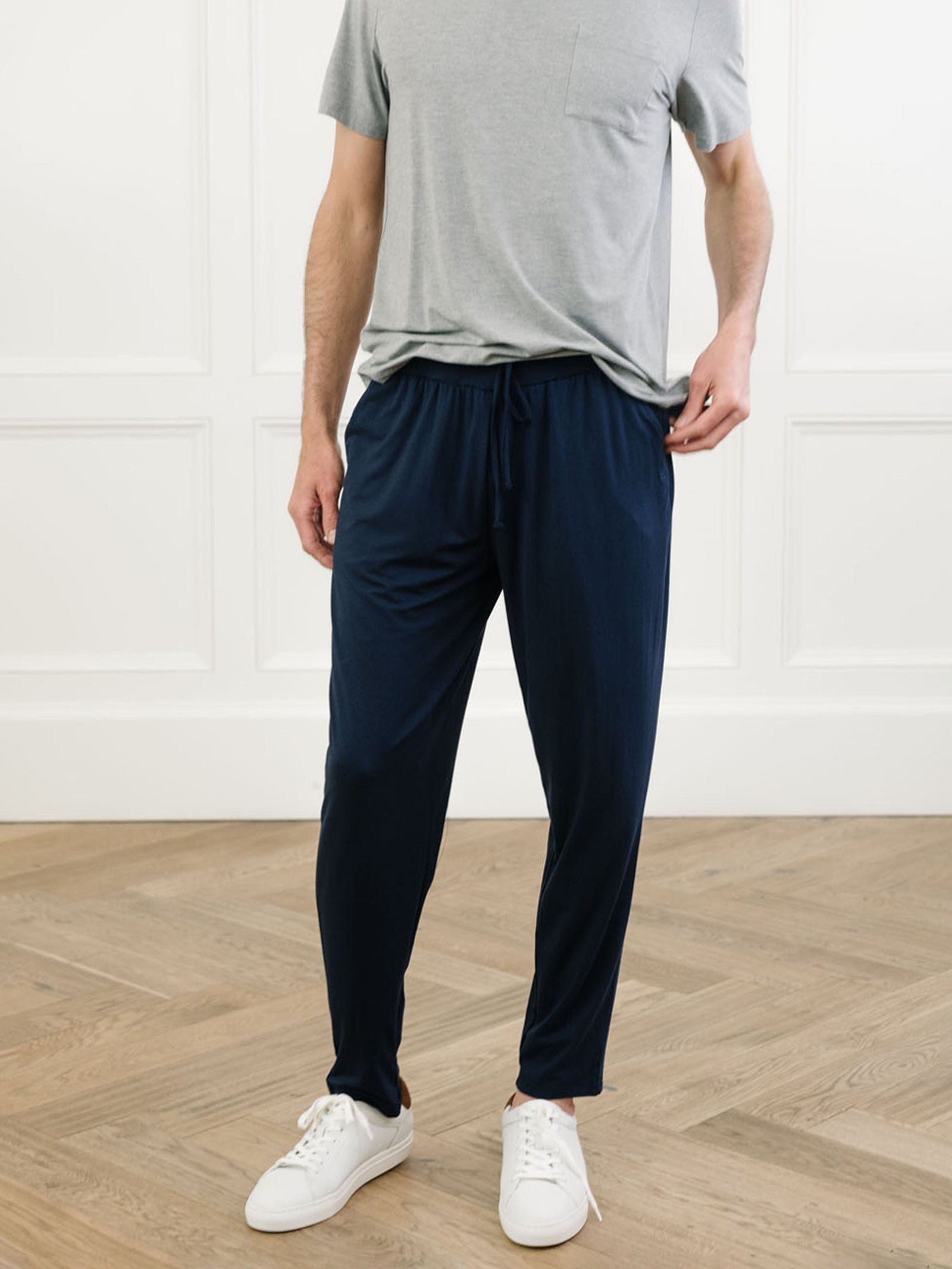 Man in navy pajama pants in room with wooden floor 