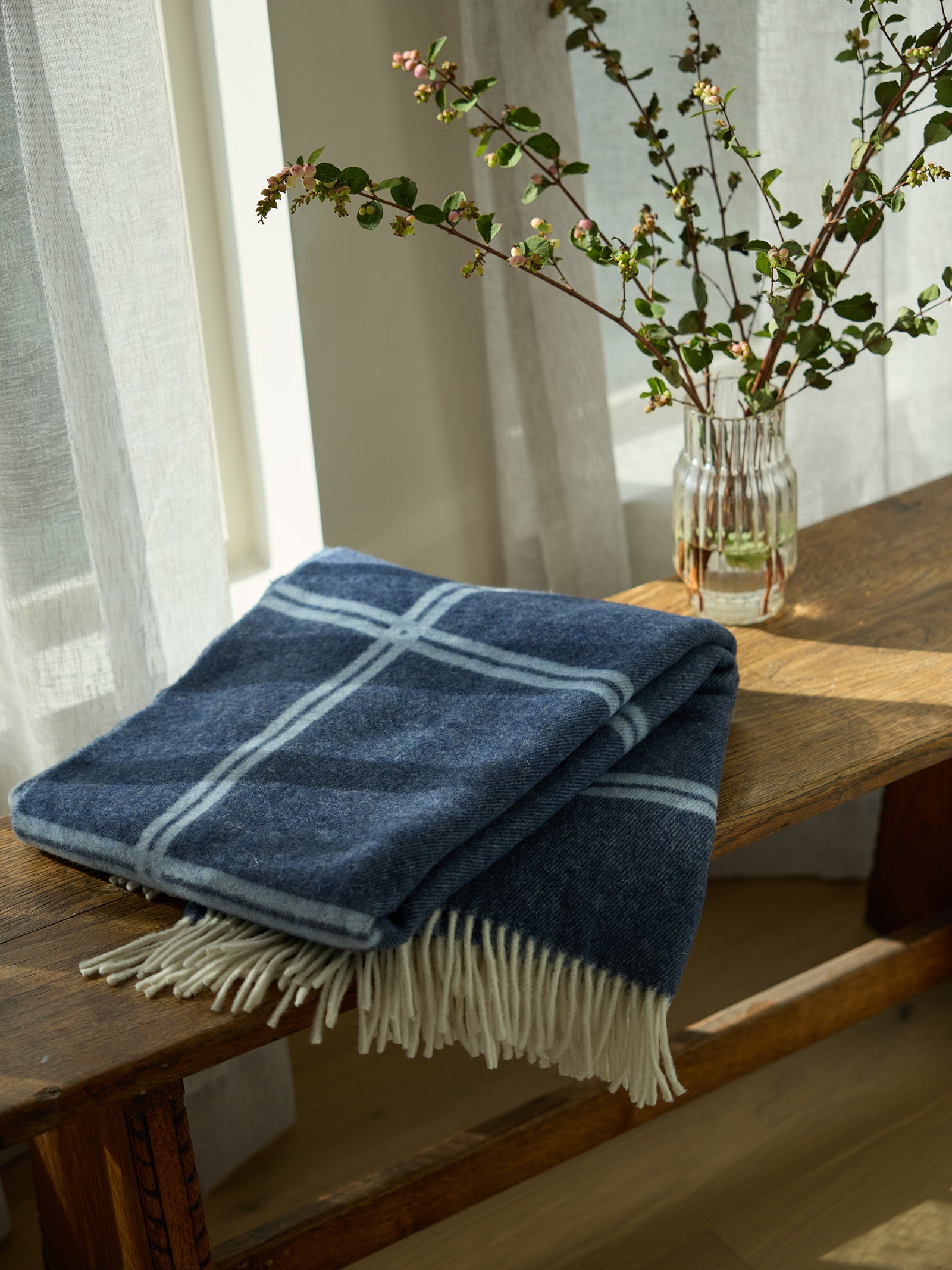 Navy cortina throw folded on wooden bench 