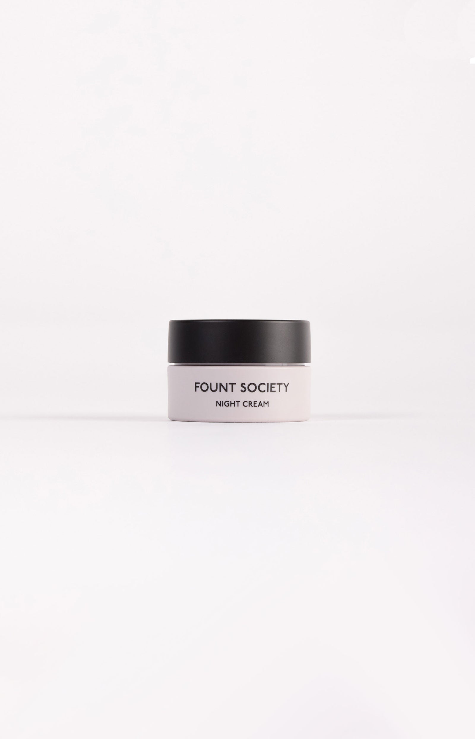 A small jar of Cozy Earth Night Cream featuring a black lid and white container, set against a plain white background. 