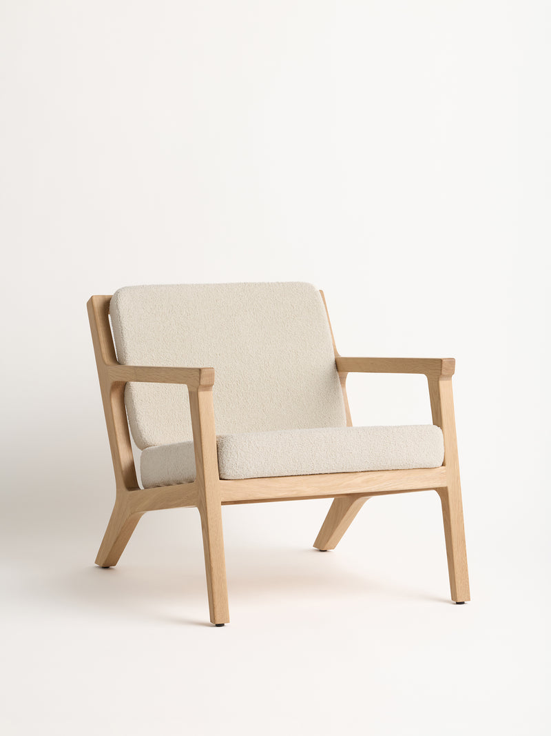 The Coronado Lounge Chair by Cozy Earth features a modern, minimalist design with a light wood frame and beige cushions, elegantly showcased against a plain white background.