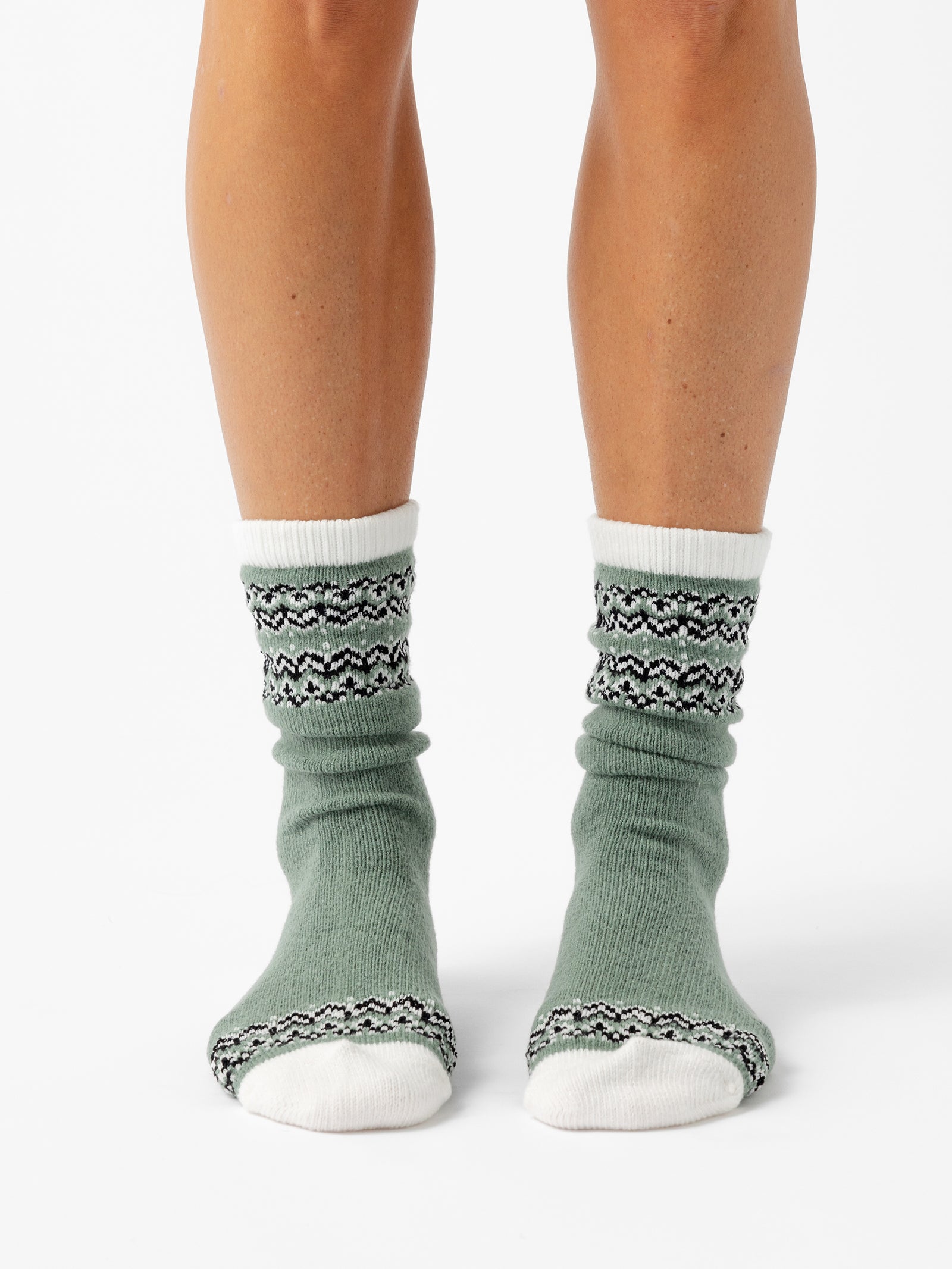 A person stands facing forward in front of a white background wearing Fair Isle Plush Lounge Socks in Oakmoss. 