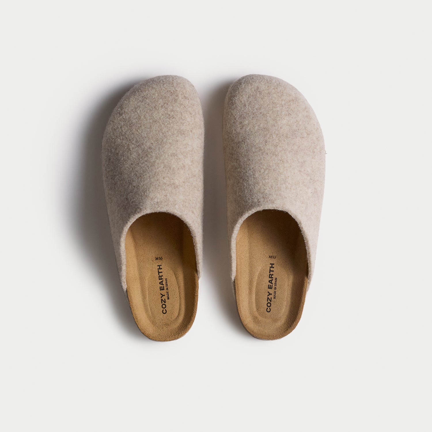 A top-down view of Cozy Earth's Lakehouse Clog, a pair of beige slip-on slippers with a soft texture and simple rounded design, set against a white background. |Color:Oat