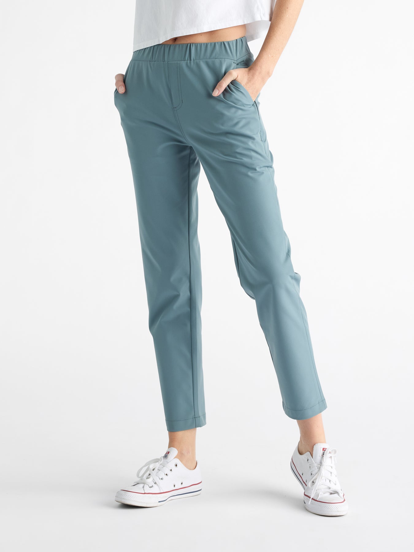 A person in Cozy Earth's Women's Always Cropped Pant in light blue-green, with hands in pockets, paired with a cropped white shirt and white sneakers against a plain white background. |Color:Oceanside