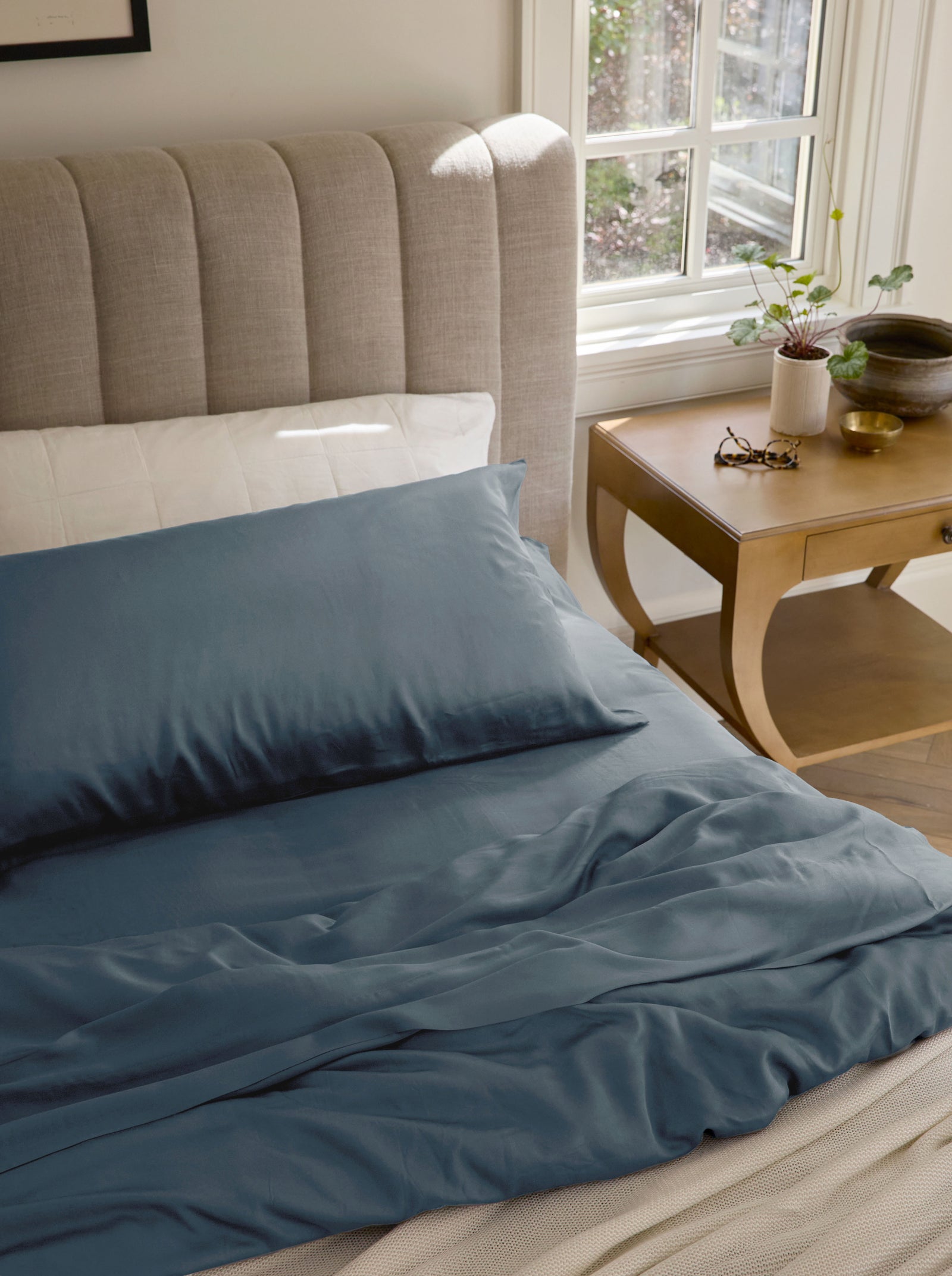 Pacific blue bedding on an unmade bed with a nightstand to the side standard/king/body