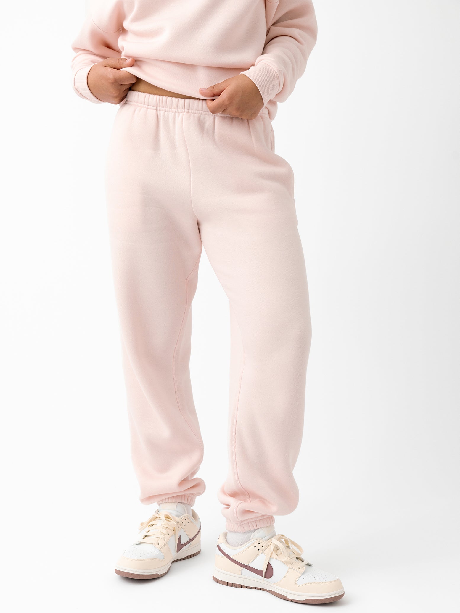 Peony CityScape Joggers. The Joggers are being worn by a female model. The photo is taken from the waist down with the models hands by the pocket of the joggers. The back ground is white. |Color:Peony