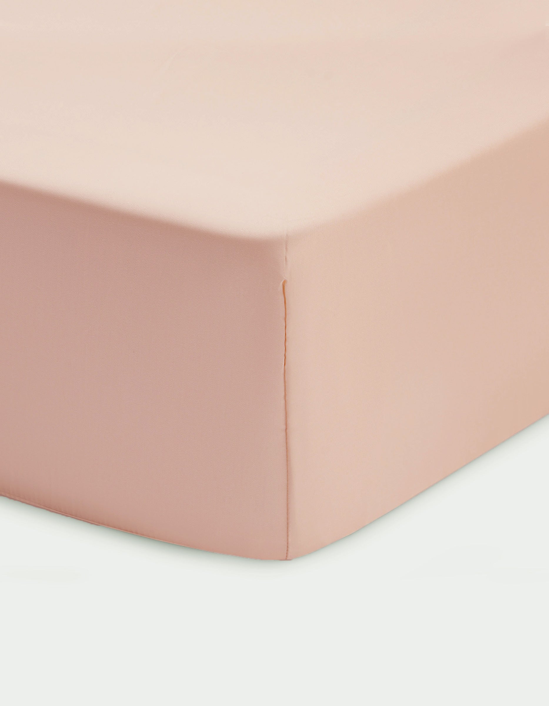 Close-up of a Cozy Earth Bamboo Fitted Sheet in light pink, smoothly covering a mattress with neat stitching and soft fabric.