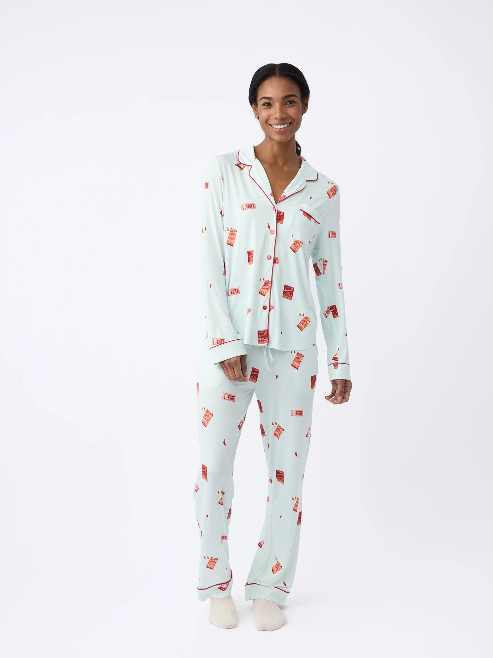 A person smiles, wearing Cozy Earth Women's Long Sleeve Bamboo Pajama Top in Stretch-Knit with a red and white print. They stand against a plain white background with their hands at their sides. 