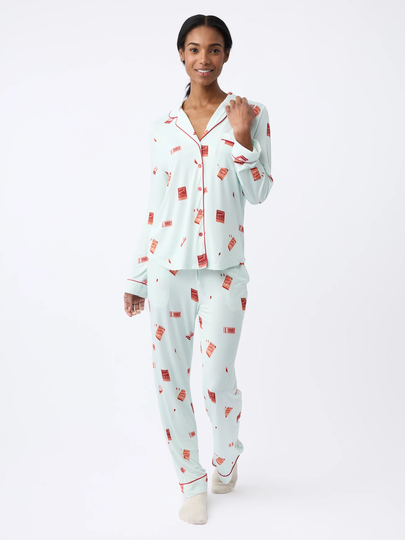 A person wearing Cozy Earth Women's Stretch-Knit Bamboo Pajama Pant in light blue with a red rectangular pattern walks forward against a plain white background, displaying a relaxed and cheerful expression. 