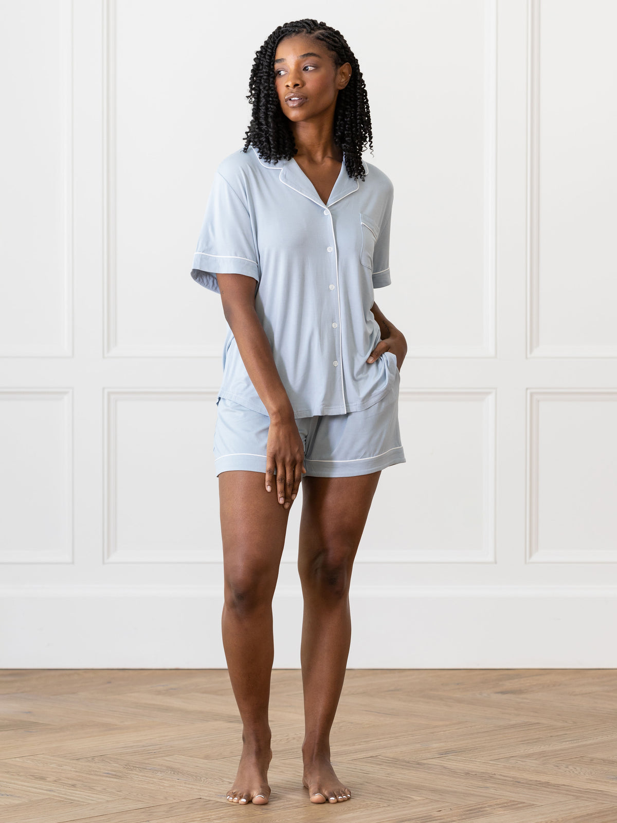 Powder Blue Short Sleeve Pajama Set modeled by a woman. The photo was taken in a light setting, showing off the colors and lines of the pajamas. 