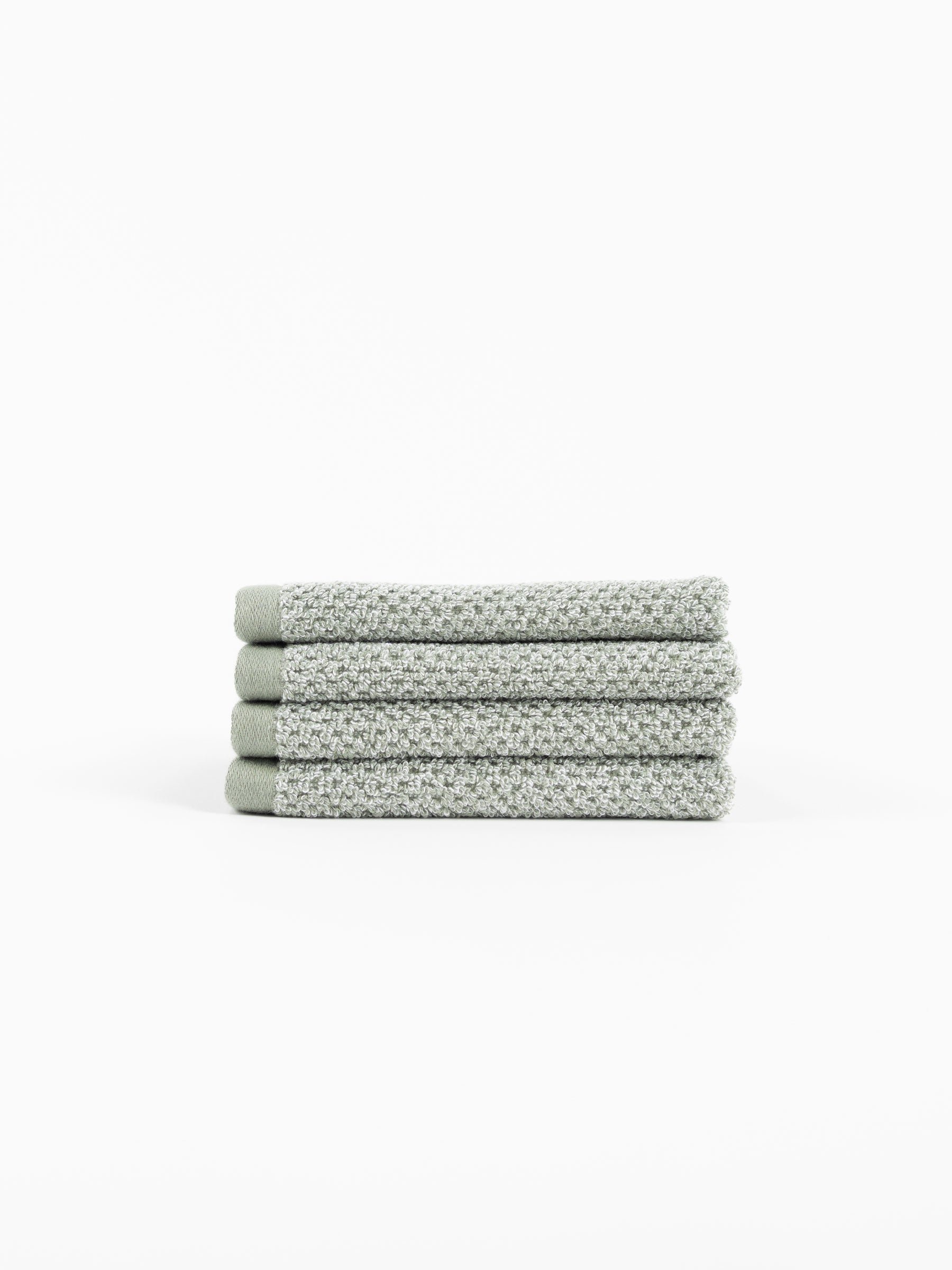 A stack of four Nantucket Washcloths in Heathered Sage sit in front of a white background. 