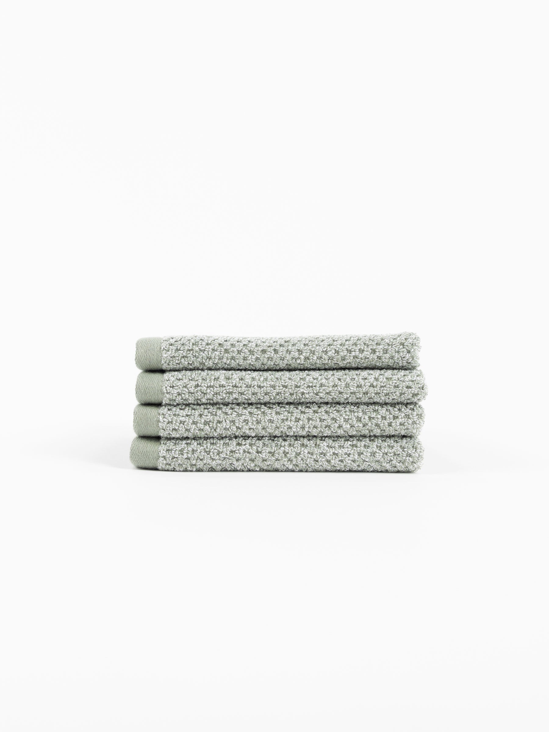 A stack of four Nantucket Washcloths in Heathered Sage sit in front of a white background. 