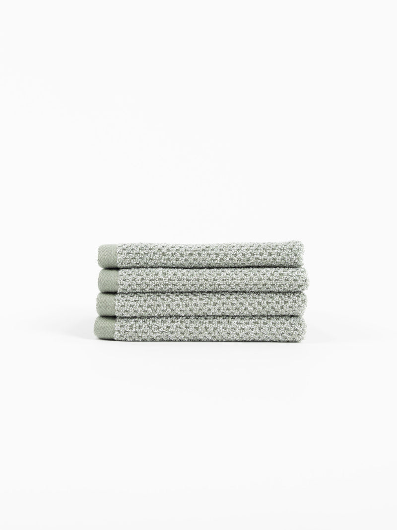 A stack of four Nantucket Washcloths in Heathered Sage sit in front of a white background.