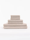 The Cozy Earth Nantucket Bath Towel Set features beige textured towels in various sizes, neatly stacked from largest to smallest, set against a plain white background.|Color:Heathered Sand