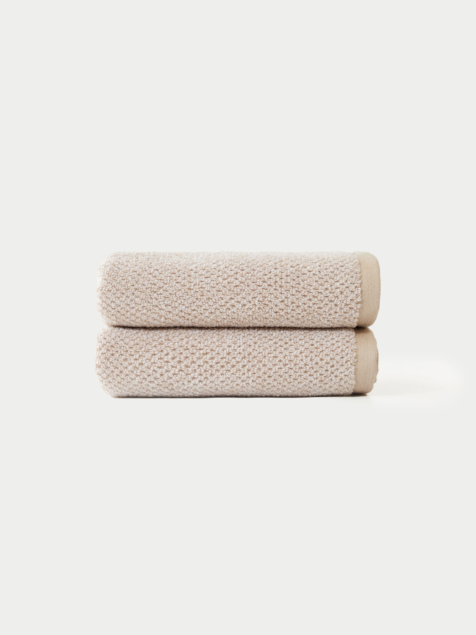 Two Nantucket Bath Towels by Cozy Earth, neatly folded and stacked atop each other, are displayed against a plain white background.