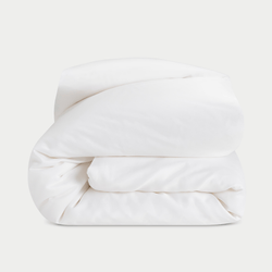 A neatly folded, fluffy Silk Comforter by Cozy Earth is placed against a plain light background. The fabric appears smooth and soft, highlighting its plush and inviting texture.